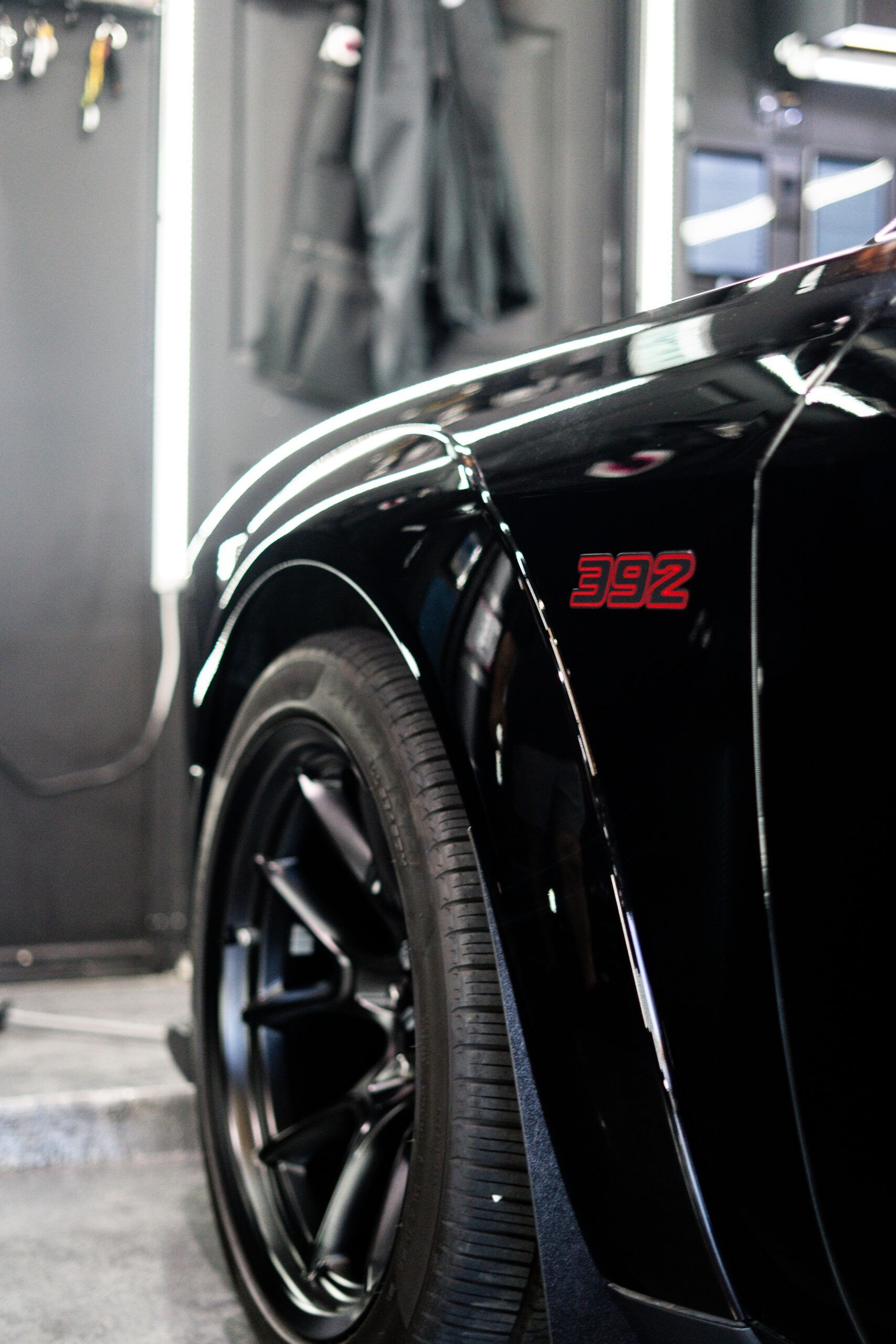 A man is cleaning a red sports car in a garage.