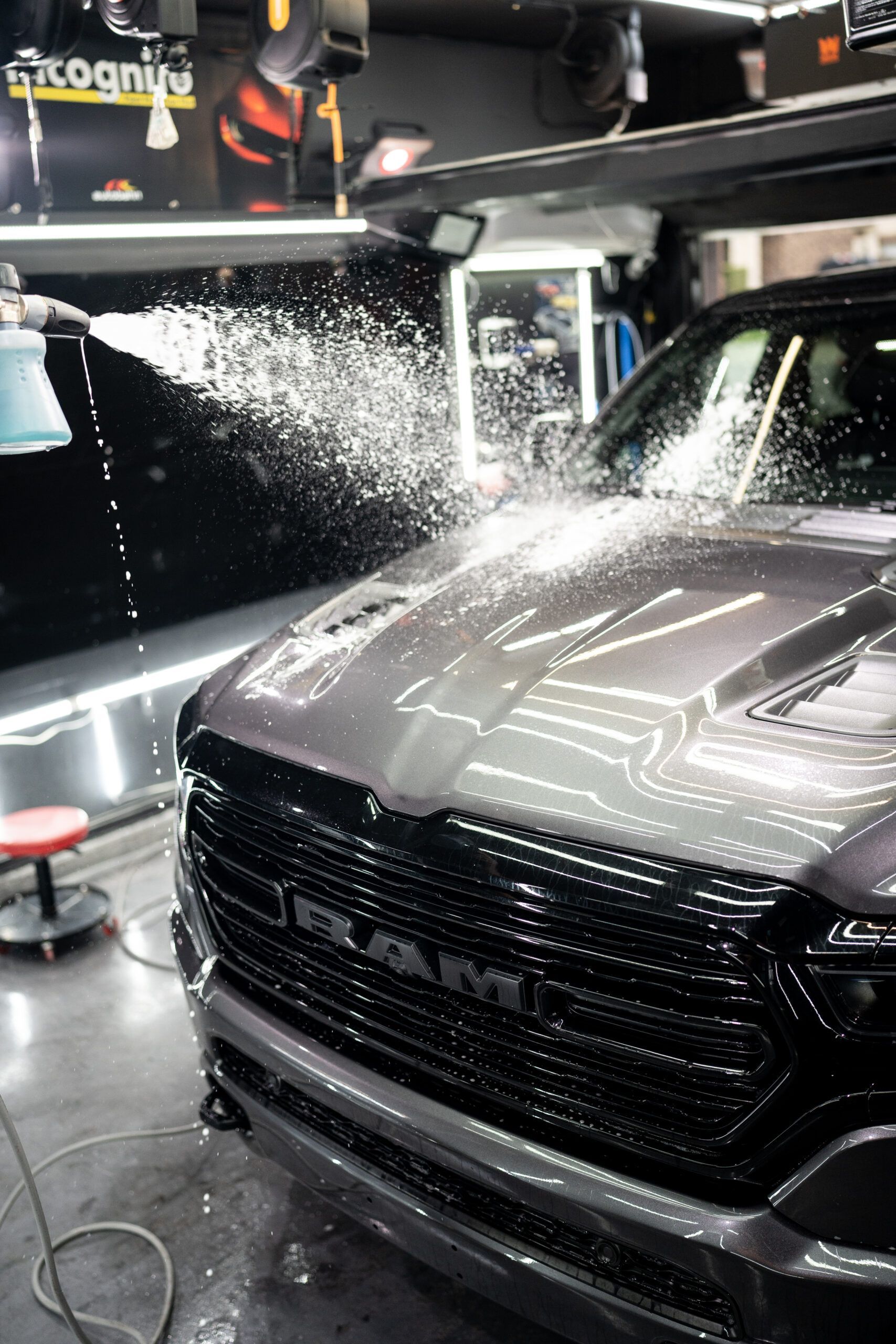 A man is washing a red sports car in a garage.