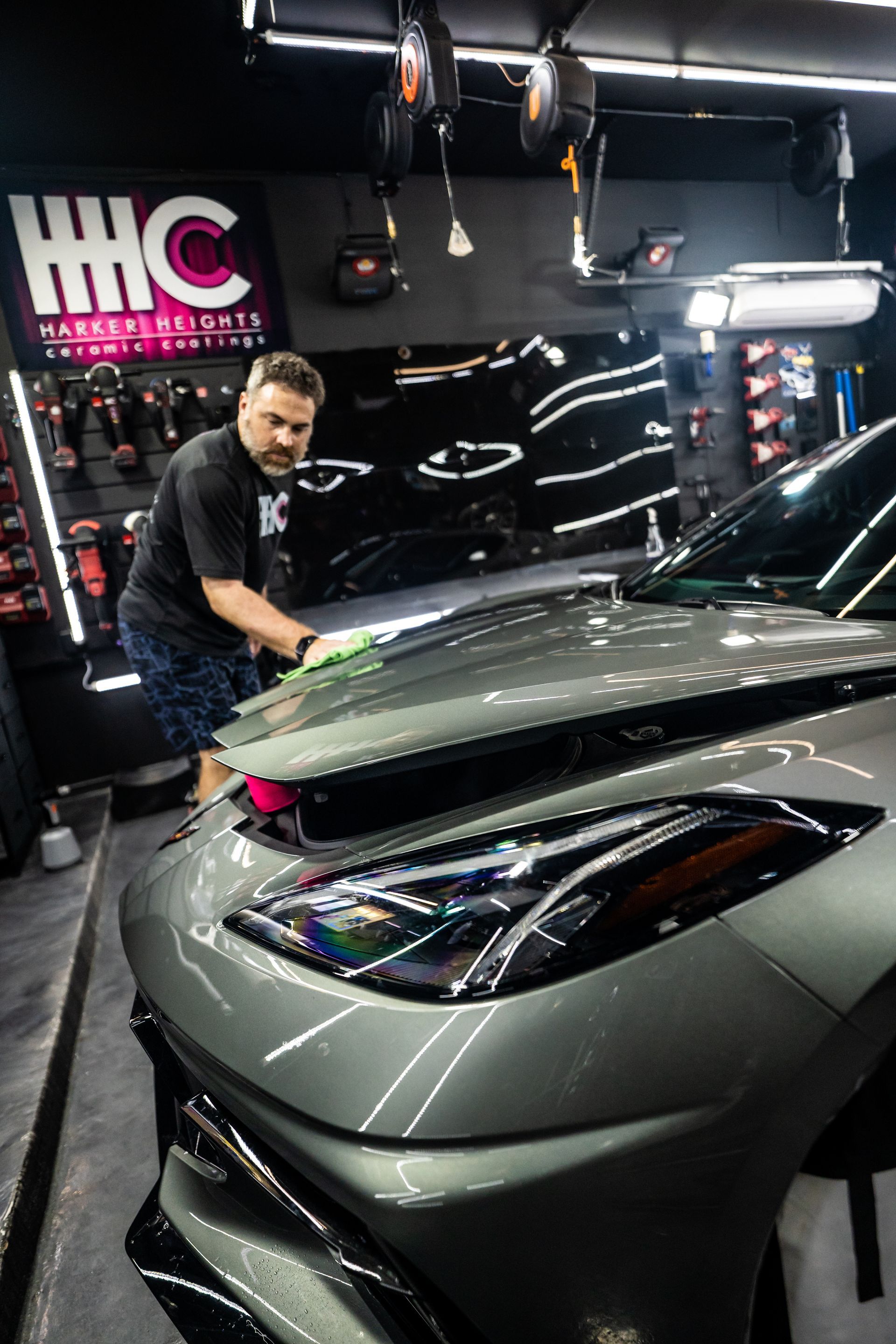 A man is cleaning the hood of a car in a garage.