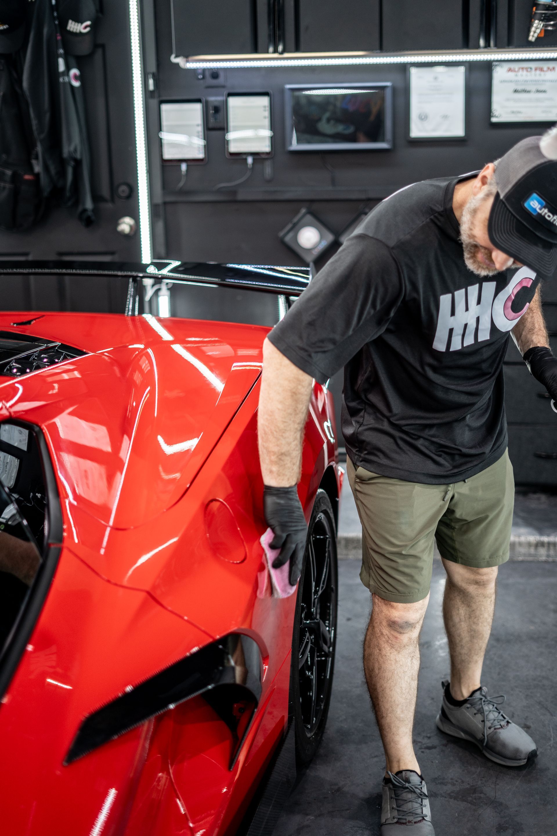 A man is standing next to a red sports car in a garage.