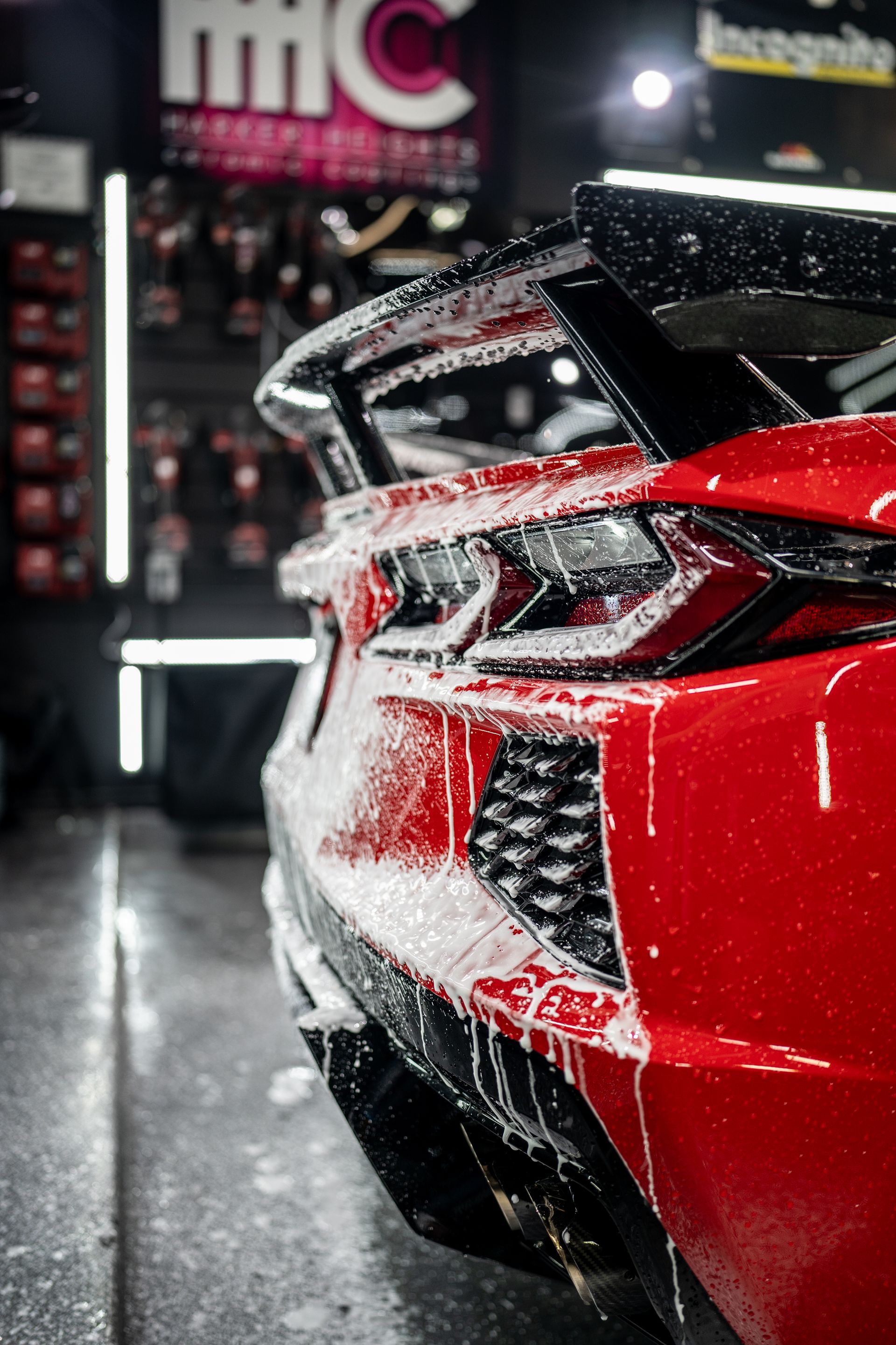 A red sports car is being washed in a garage.