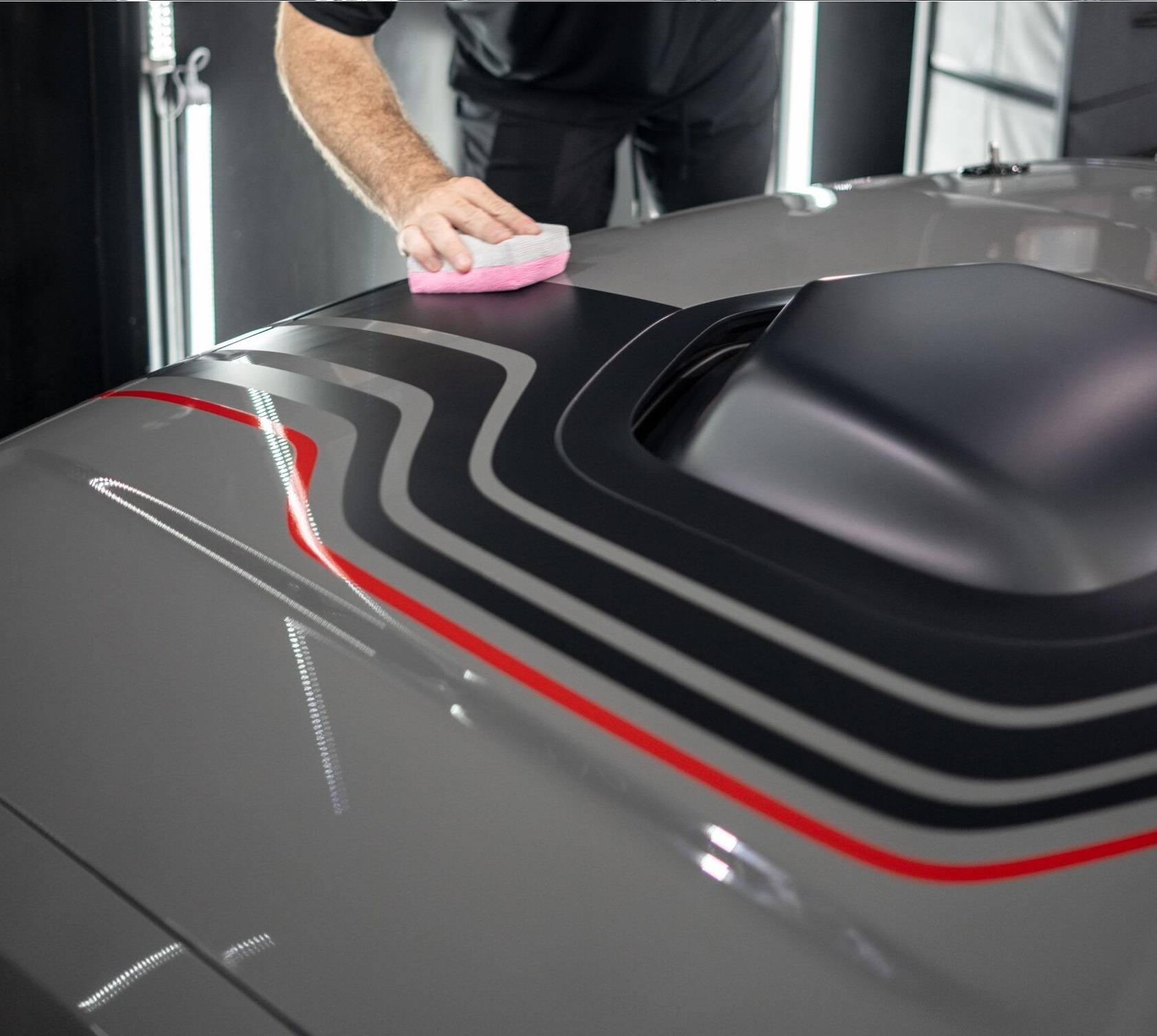 A man is cleaning a car in a garage.