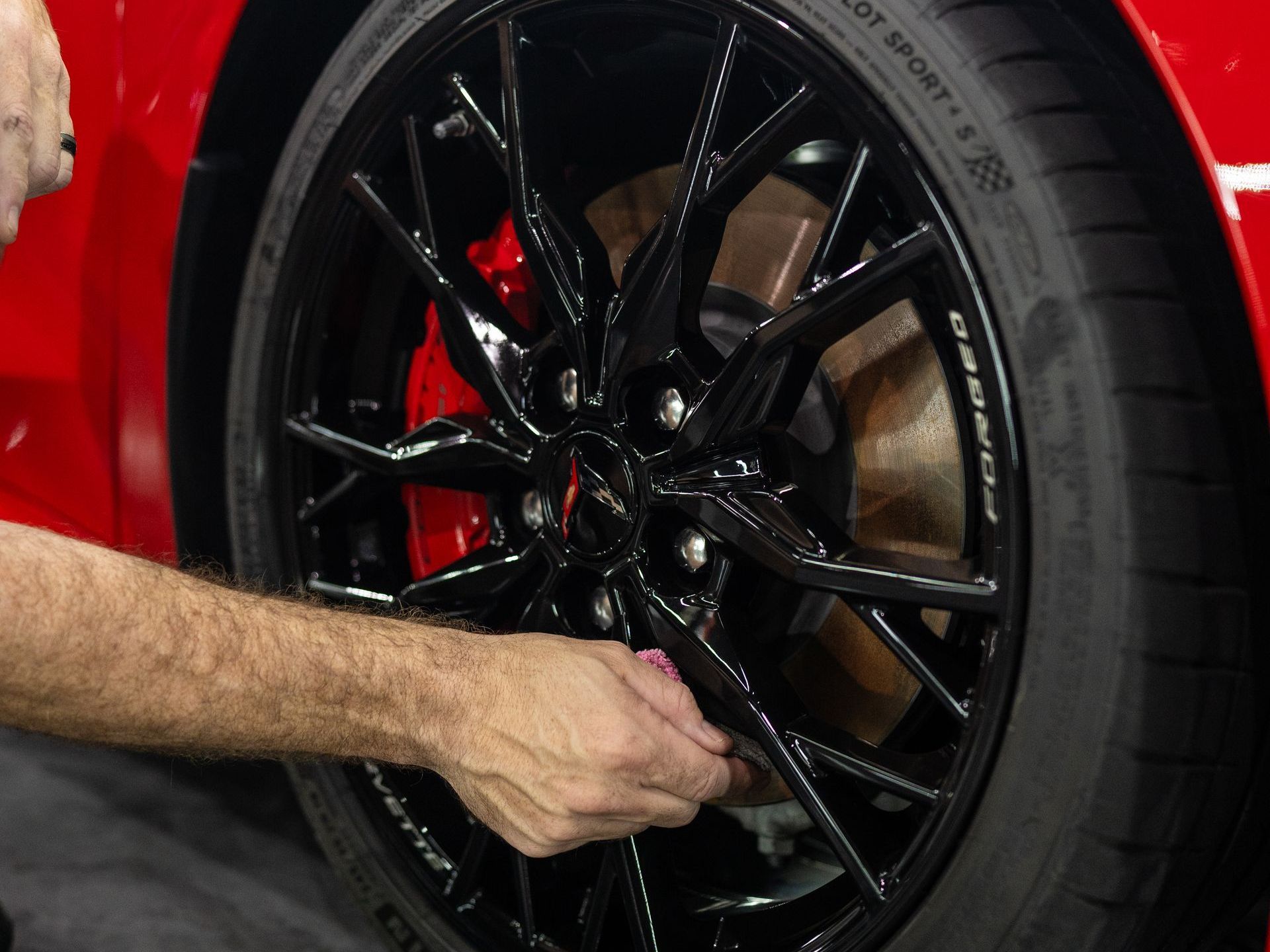 A man is changing a tire on a red car