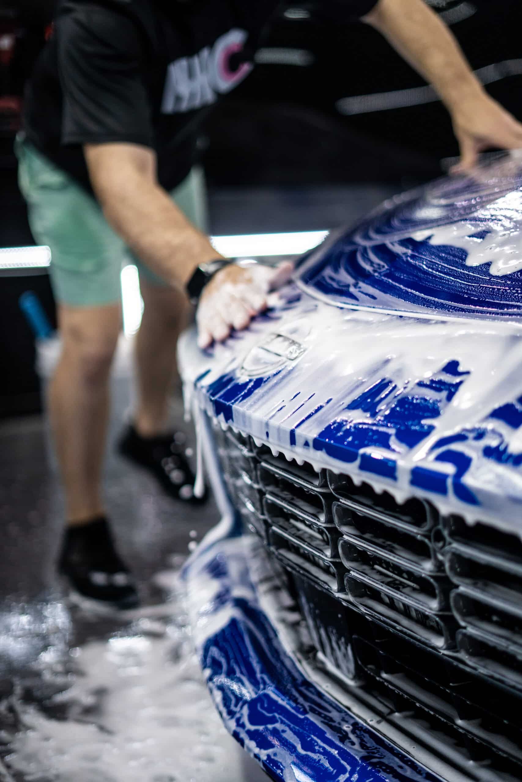 A man is washing a car with soap and water.